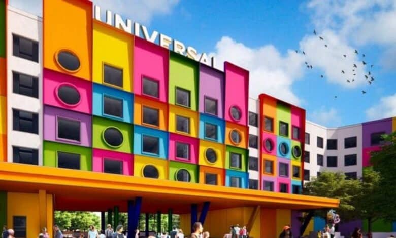 A colorful hotel with a bold, modern design featuring square and circular windows, bright panels in orange, green, yellow, and pink, with “UNIVERSAL” on the roof, and people gathered outside in Texas.