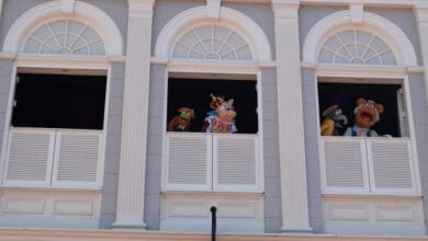 Four muppets stand and perform in windows in Libery Square.