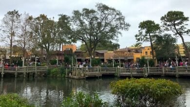 People walking through Frontierland at Magic Kingdom Park as seen from Tom Sawyer Island across the Rivers of America.