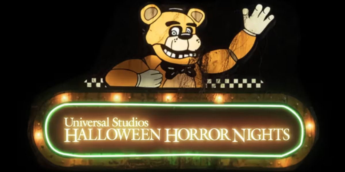 A neon sign for Universal Studios Horror Nights features a cartoonish animatronic bear waving, resembling a character from Five Nights at Freddy’s, above glowing text framed in eerie green lights.