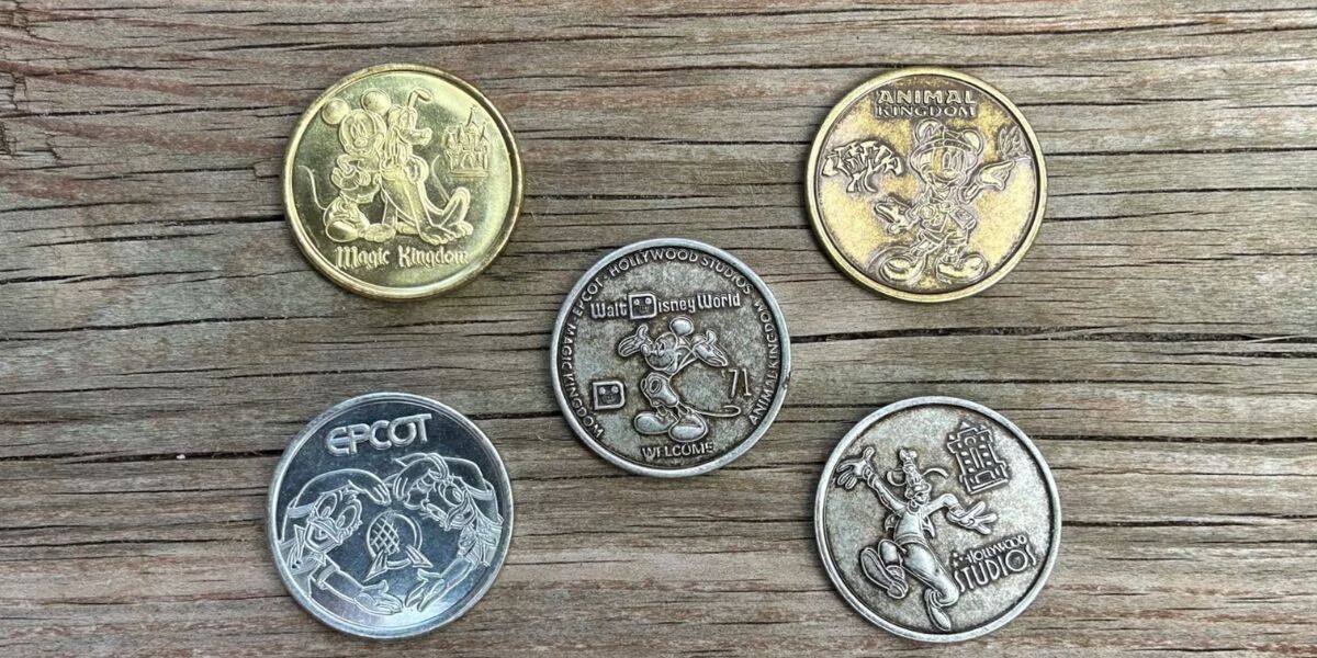 Five commemorative souvenir Disney World coins on a table.