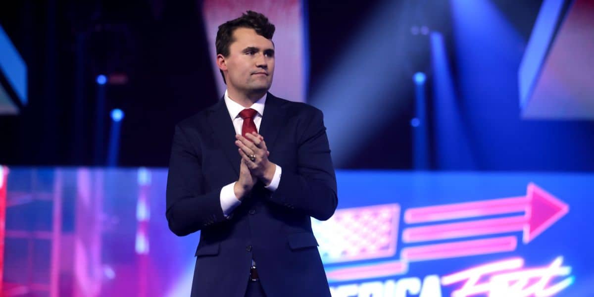 Charlie Kirk claps on a stage.