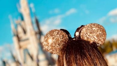 guest wearing gold mickey ears in front of disney world's cinderella castle in magic kingdom