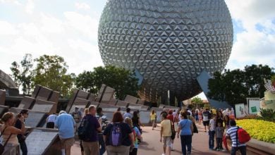 A crowd of people walk toward Epcot’s large geodesic sphere, Spaceship Earth.
