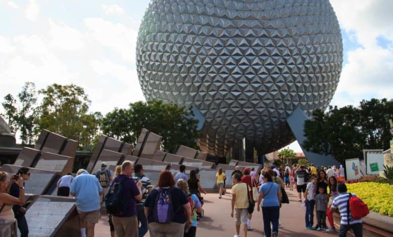A crowd of people walk toward Epcot’s large geodesic sphere, Spaceship Earth.