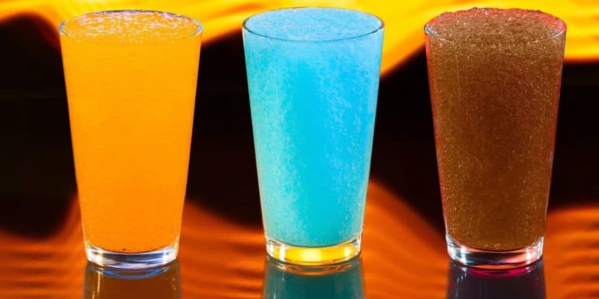 Three glasses of slush drinks—orange, blue, and brown