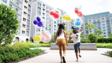two kids running with mickey-mouse shaped balloons at disney hotel