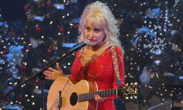 Dolly Parton performing with a guitar on stage at Dollywood at Christmastime.