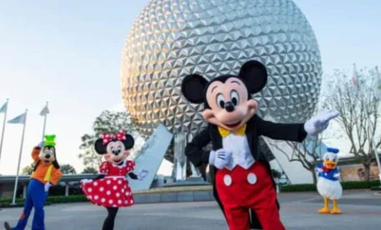 Mickey Mouse, Minnie Mouse, Goofy, and Donald Duck pose in front of spaceship earth in Disney World's EPCOT park.