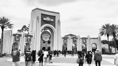 A crowd of people walk toward the large arched entrance of Universal Studios Florida