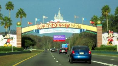 Vehicles pass beneath the iconic Walt Disney World Resort archway.