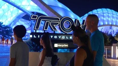family walking in front of the sign for Tron Lightcycle Run in Disney World's Magic Kingdom park