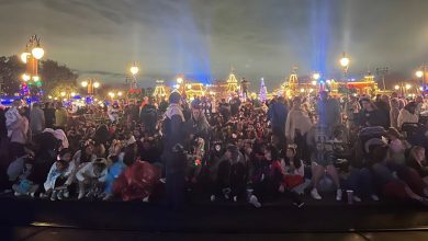 Excited guests fill Main Street, U.S.A. at night, eagerly awaiting the illuminated parade at Magic Kingdom.