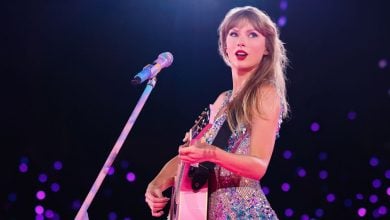 Taylor Swift holding a guitar during the "Lover" set at The Eras Tour