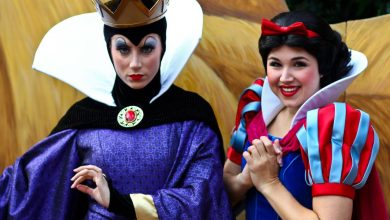 The Evil Queen and Snow White greet guests in vibrant costumes at a lively Disney park meet-and-greet outdoors.