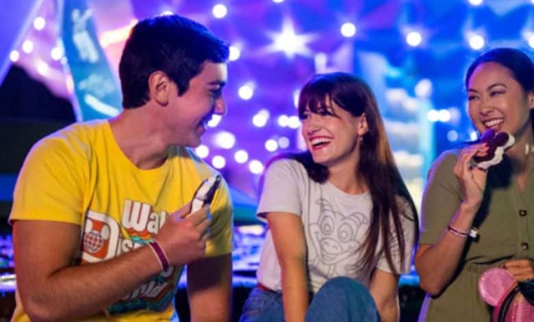 Three Disney World guests enjoy ice cream in front of EPCOT's Spaceship Earth at night