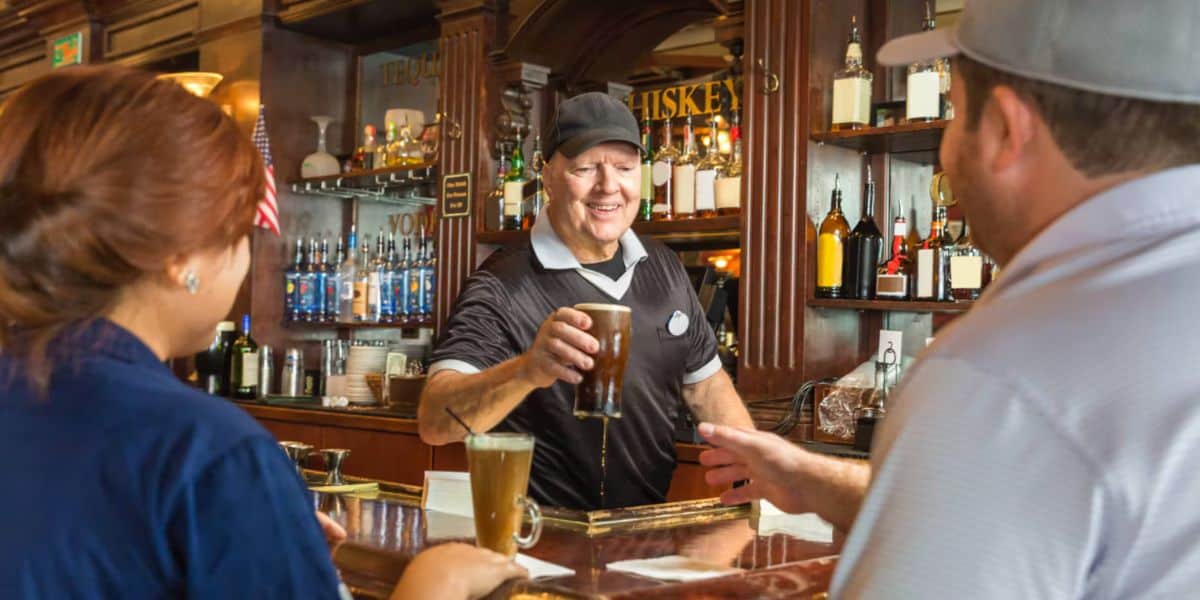 Inside Universal Bar, a cheerful bartender serves drinks to guests, creating unforgettable moments—even during heartfelt goodbyes.