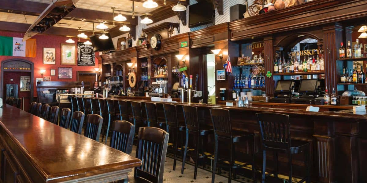A lively themed bar with a long wooden counter, high stools, and shelves of bottles—ideal for park-goers to gather and celebrate.