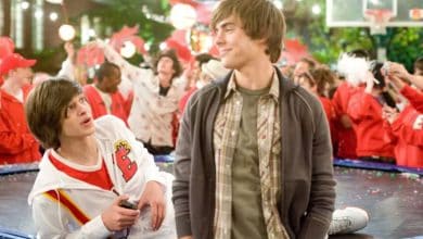 Two teenage boys laugh and chat amid a crowd of excited classmates at a spirited school pep rally.