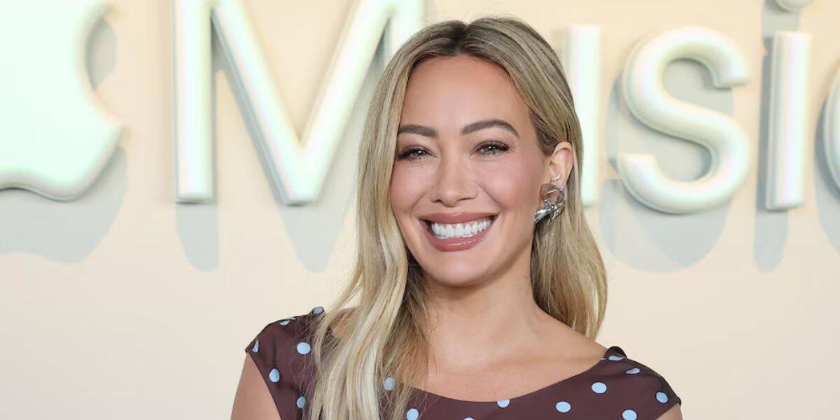 Hilary Duff lookalike beams in a brown polka dot dress by the Apple Music sign, ready to burst into Disney-style song.