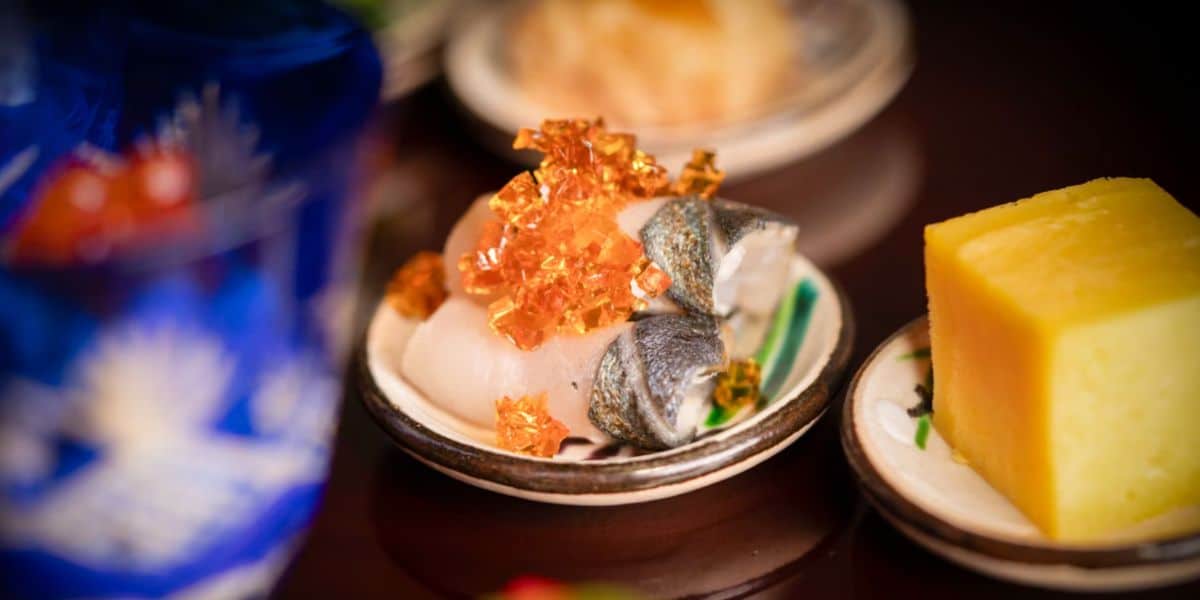 Gourmet sushi with gold flakes and a yellow dessert cube, served at EPCOT—perfect for Disney foodies seeking luxury bites.