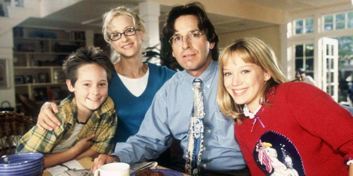 A cheerful family of four gathers around a table in a vibrant, theme park-inspired home, sharing smiles and support.