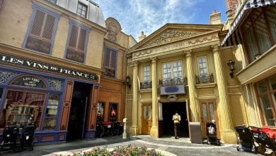 Parisian-inspired facades at EPCOT with a wine shop, cinema, strollers, and flowers near the 43-year-old closed attraction.