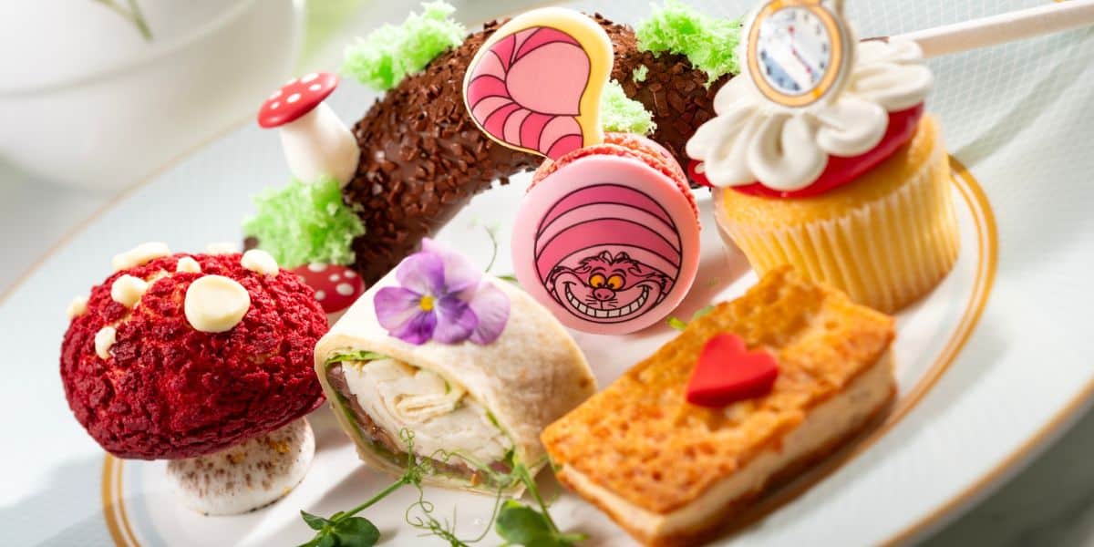 Alice in Wonderland dessert plate at Disneyland, featuring vibrant pastries and a whimsical Cheshire Cat macaron.