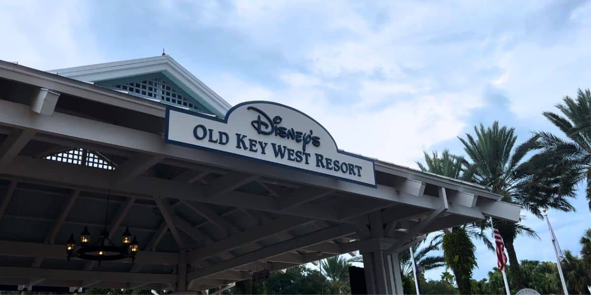 Disney’s Old Key West Resort entrance sign with swaying palms and a cloudy sky, inviting fans to enjoy Disney magic by a favorite eatery.