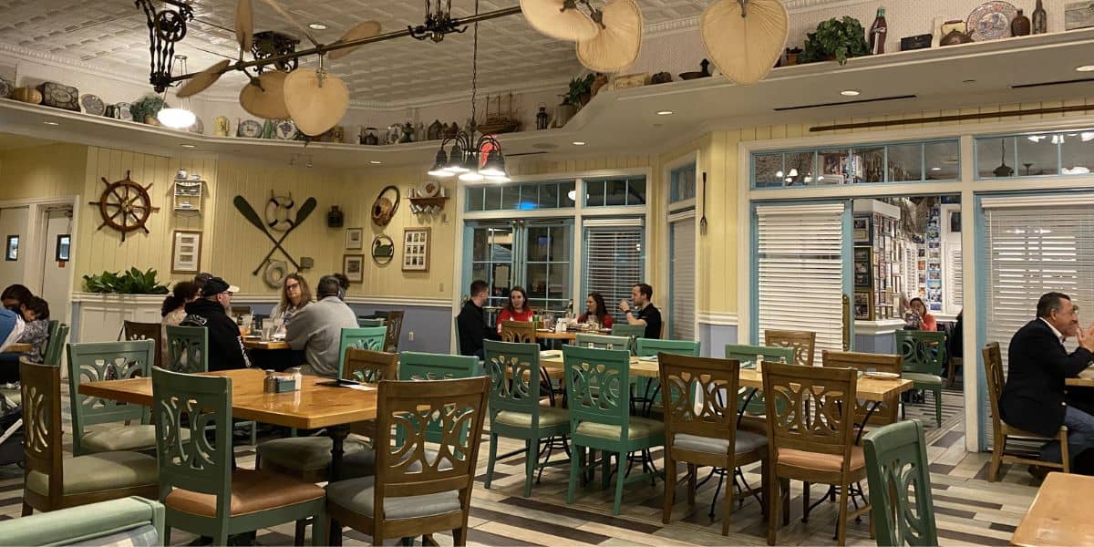 Step into a Disney eatery filled with nautical touches, green chairs, and guests reliving classic memories at wooden tables.