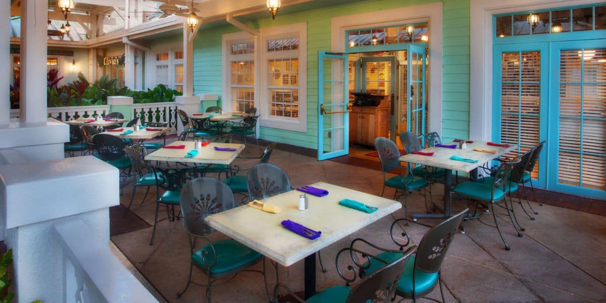 Charming patio dining area with empty tables, napkins set, near colorful doors—ideal for gathering after a fun day at the park.