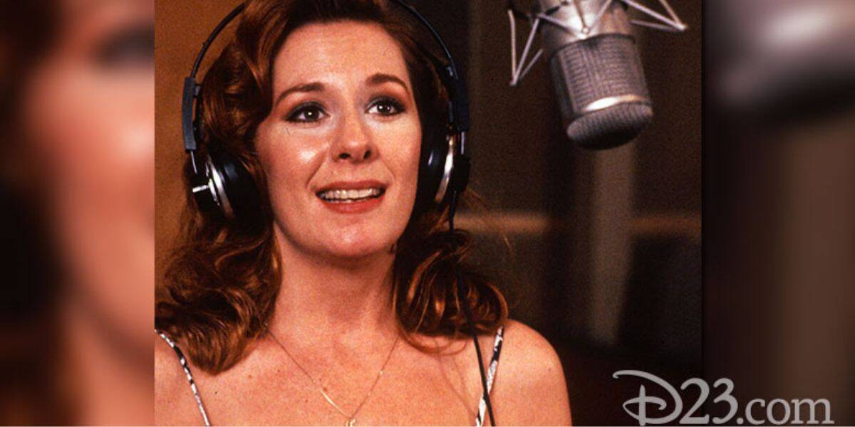 Belle’s voice actress records in the studio, headphones on, bringing Disney magic alive. “D23.com” is seen in the corner.
