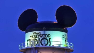 The iconic Mickey Mouse-ear water tower glowing against the blue sky at Disney's Hollywood Studios, welcoming park guests.