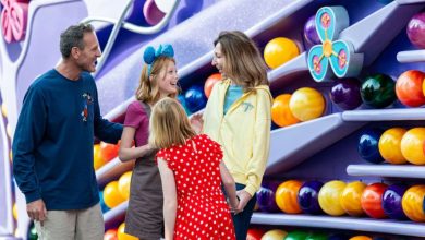 Guests laugh together in front of Inside Out-inspired vibrant ball walls at Disney California Adventure Park, near the Emotional Whirlwind ride inspired by the film.