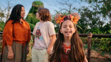 a little girl with mickey mouse ears smiles in front of EPCOT's journey of water inspired by moana attraction