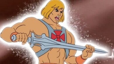 Heroic blond character wields a glowing sword amid sparkling lights, ready for adventure at a lively theme park attraction.