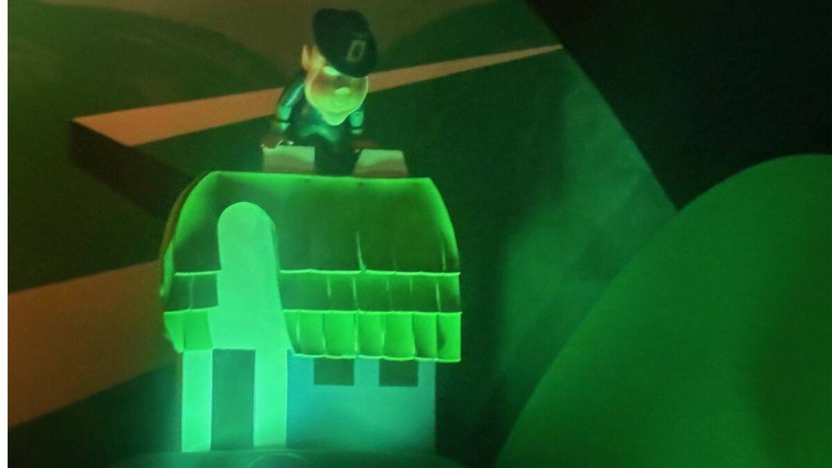 Leprechaun statue sits atop a green-lit, whimsical "it's a small world"-style cottage, exuding classic Disney charm.