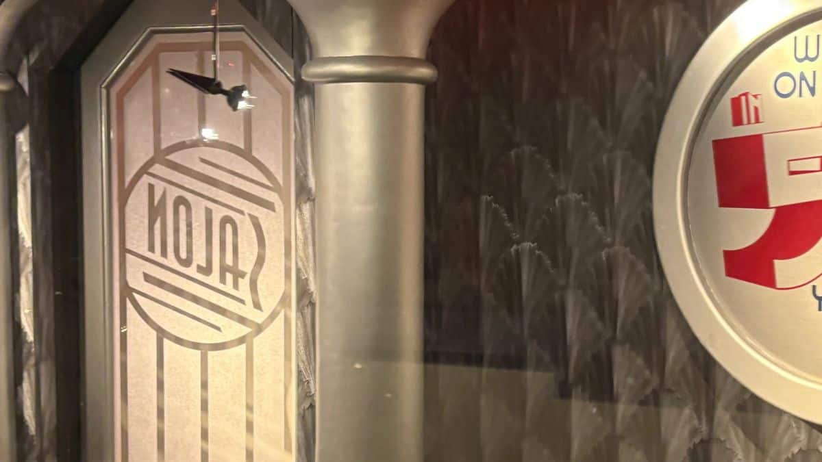 Frosted glass door with "ALOJA" and a red-white sign hint at the People Mover’s mysterious Futuristic Hair Salon in Magic Kingdom.