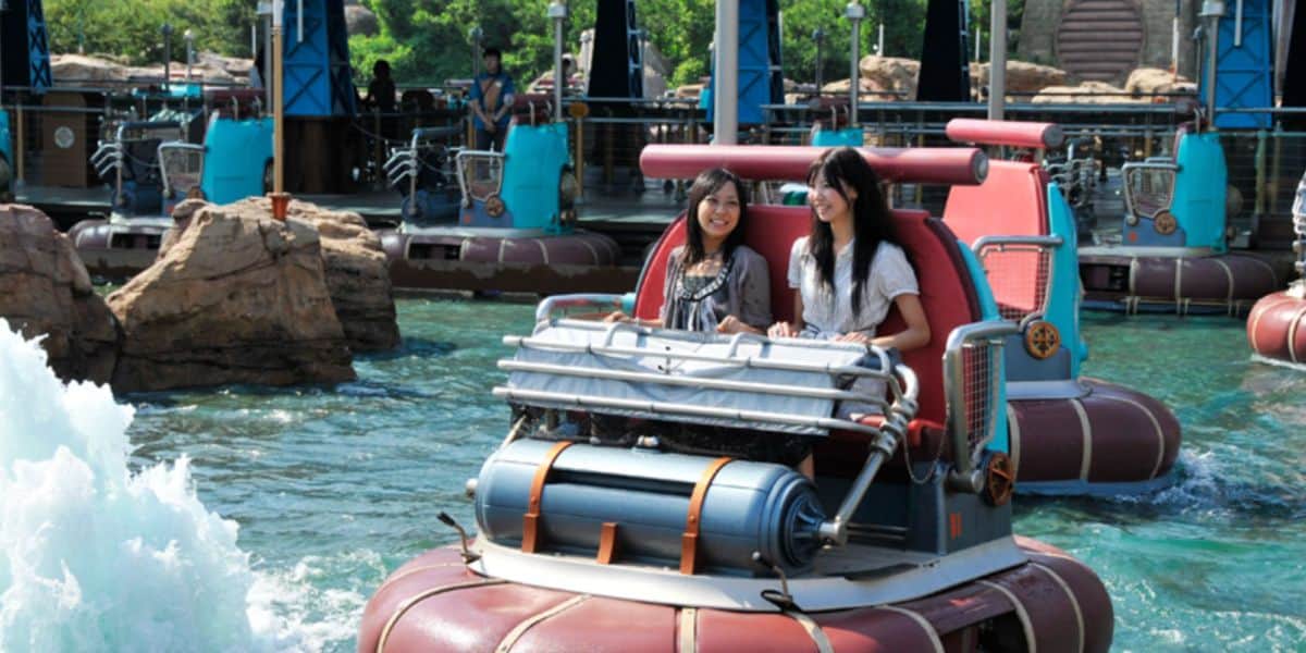 Two guests laughing on Aquatopia, splashing through rapids and rocks, highlighting park fun amid global closures.