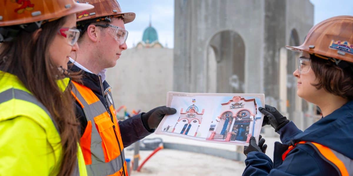 Three crew members in safety vests review a blueprint for the Up (2009) ride!