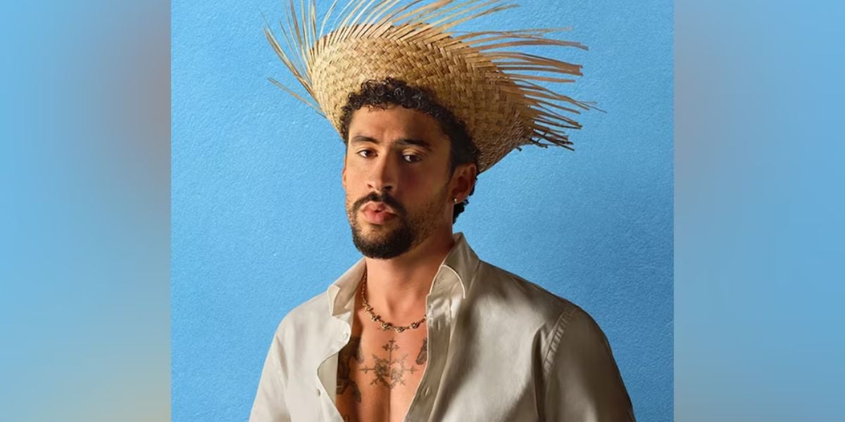 A performer dressed in a festive straw hat and open white shirt greets guests against a bright blue stage backdrop.