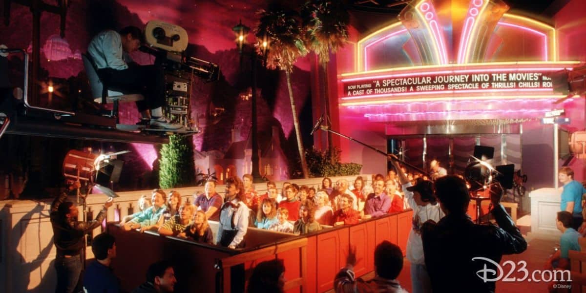 Fans gather excitedly as a film crew captures the magic outside a neon-glowing Disney theater marquee at night.