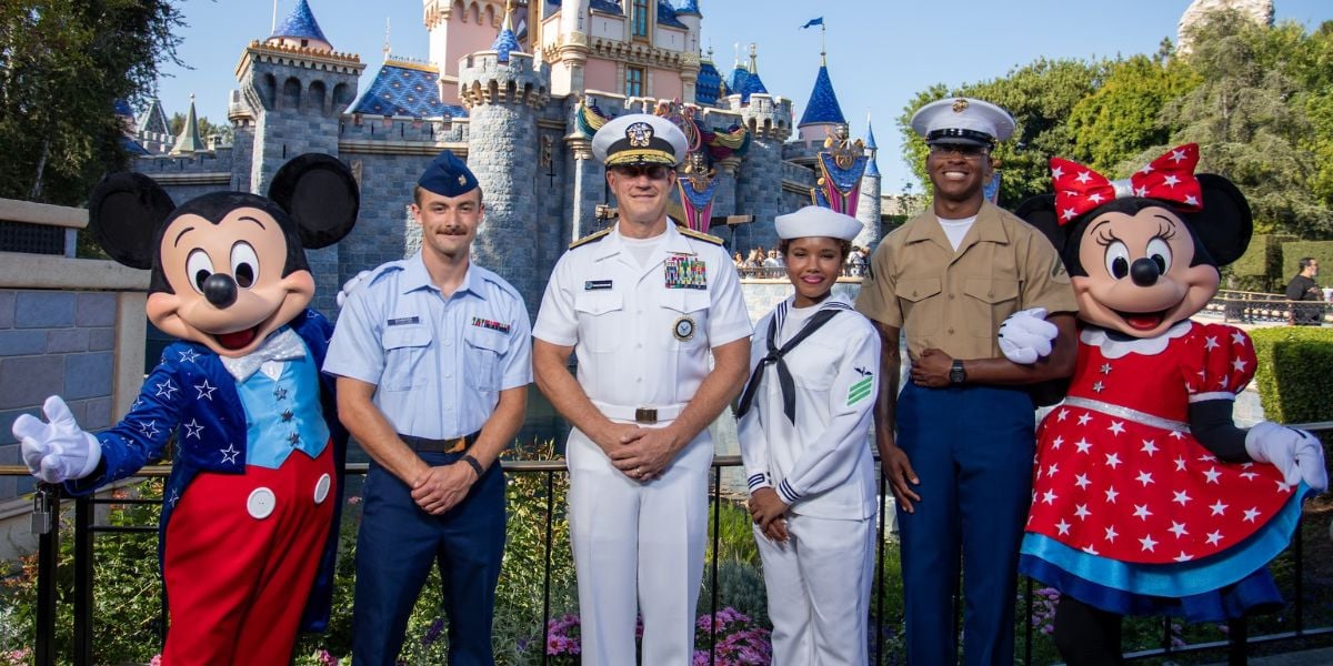 Mickey and Minnie Mouse celebrate with four U.S. military members in front of Disneyland’s iconic castle.