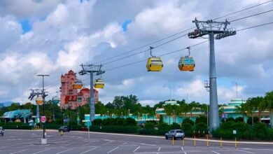 Disney Skyliner gondolas soar over the parking lot at Disney’s Hollywood Studios, with the Twilight Zone Tower of Terror in the background