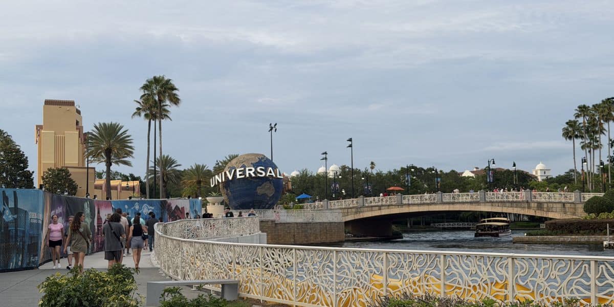 Guests stroll past vibrant murals and over a scenic bridge with the iconic Universal globe shining at Universal Orlando Resort.