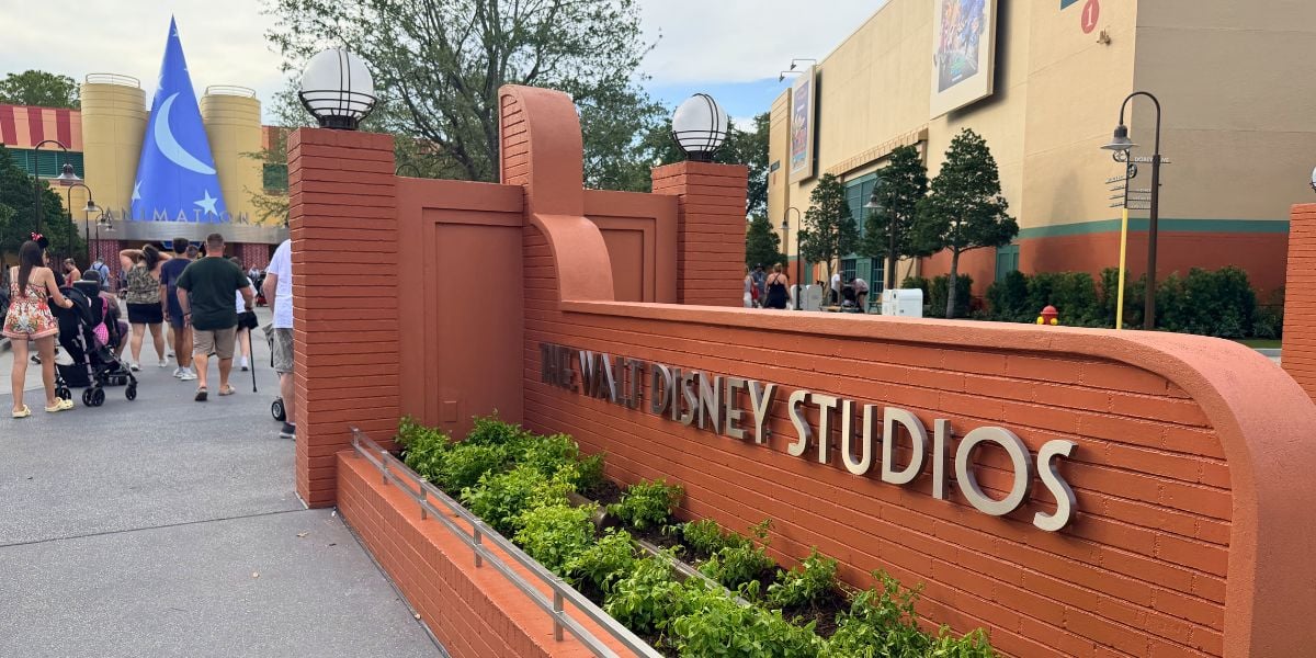 Welcome to Walt Disney Studios—pass the iconic red brick entrance and spot the magical blue Sorcerer Hat ahead!.