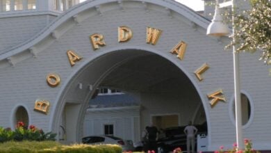 Boardwalk entrance with iconic gold lettering welcomes guests; visitors and cars pass beneath, ready for fun and entertainment.