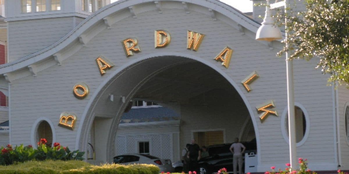 Boardwalk entrance with iconic gold lettering welcomes guests; visitors and cars pass beneath, ready for fun and entertainment.