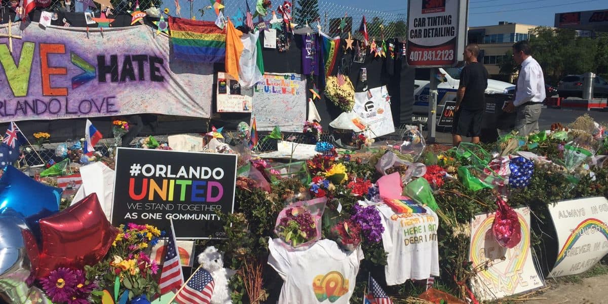 A memorial with flowers, signs, and rainbow flags honors Pulse victims; the shooter had visited Disney World before the tragedy.
