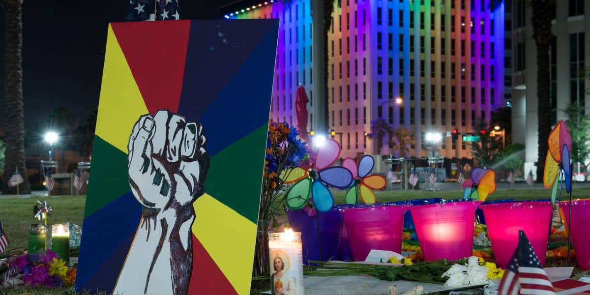 A painted fist on a rainbow background at a candlelit memorial recalls Pulse Nightclub, which was cased before Disney World was spared.